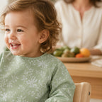 Enfant portant le bavoir à manches longues NIDOMEA vert sauge botanique pendant le repas
