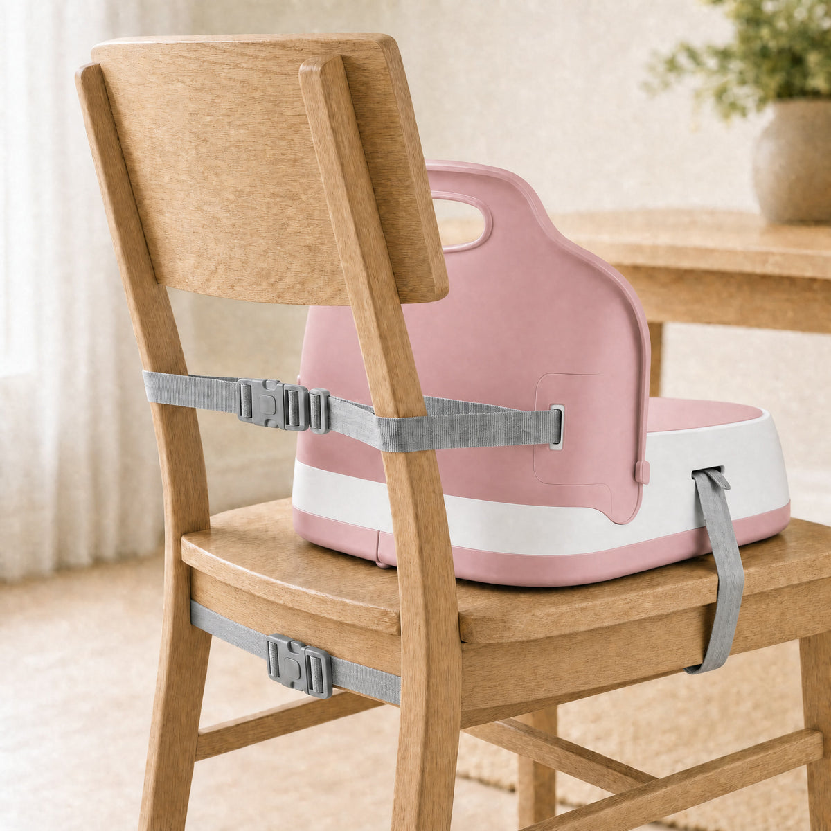 Rehausseur de chaise nomade rose poudré, sangles de fixation sur une chaise adulte
